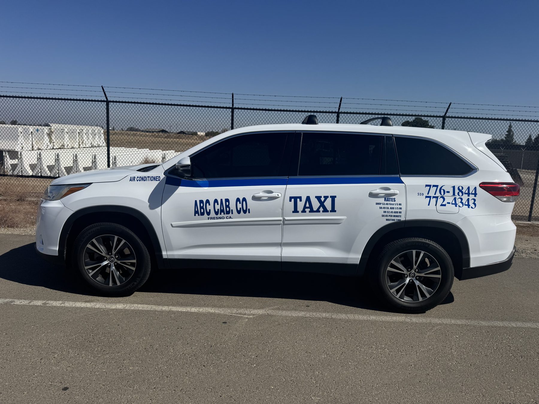 Sabi’s white ABC taxi SUV with a blue stripe, parked in Fresno